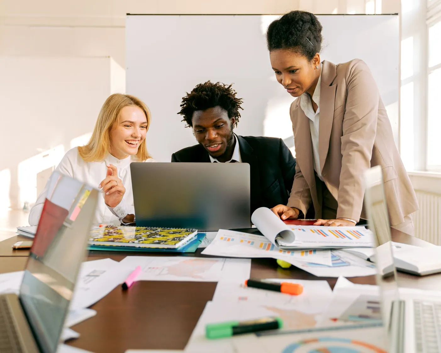 Trois professionnels collaborent autour d'un ordinateur portable dans un bureau lumineux